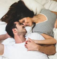 pareja acostada en una cama agarrados de la mano tu