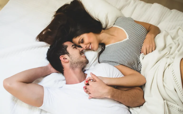 pareja acostada en una cama agarrados de la mano tu