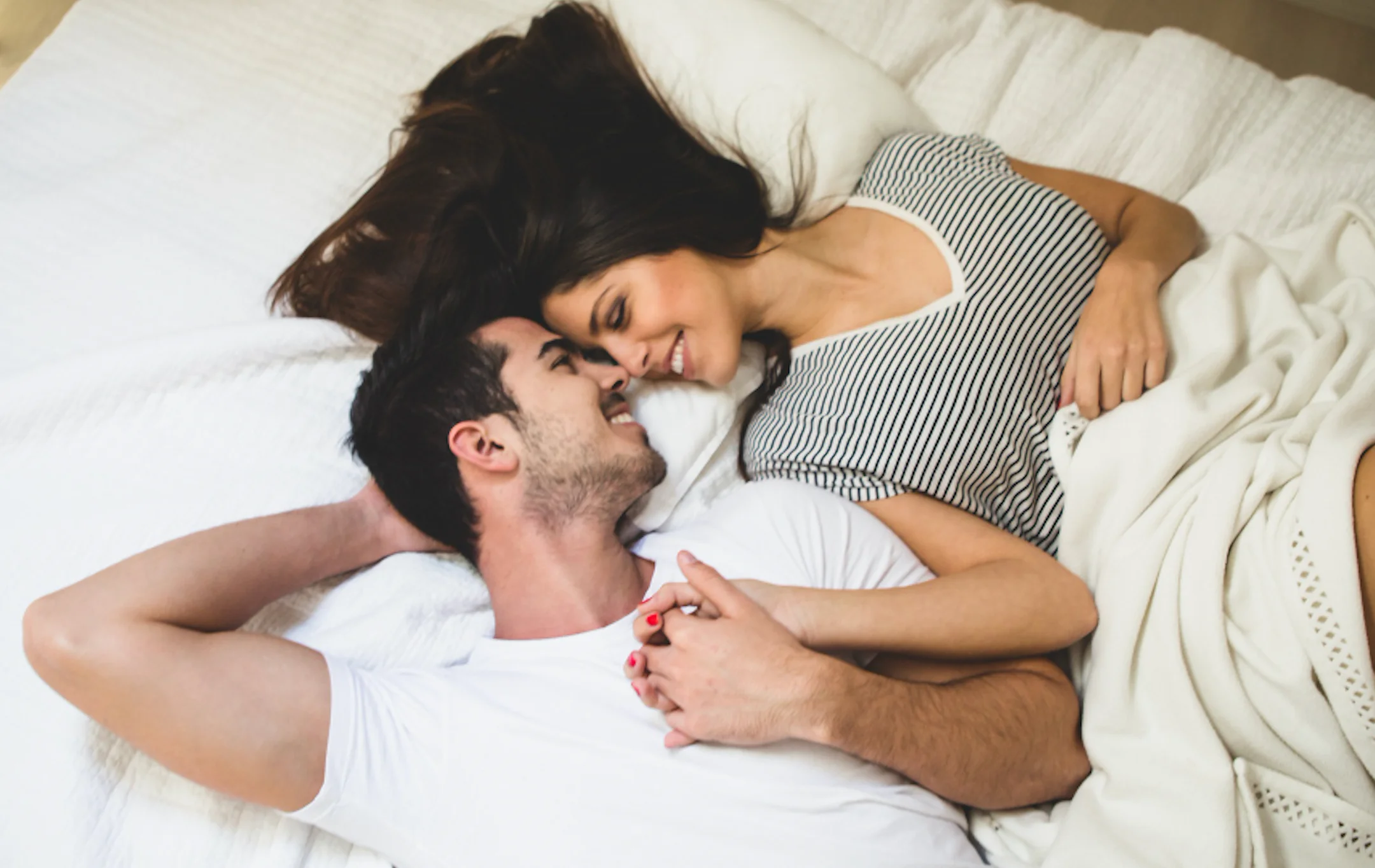 pareja acostada en una cama agarrados de la mano tu